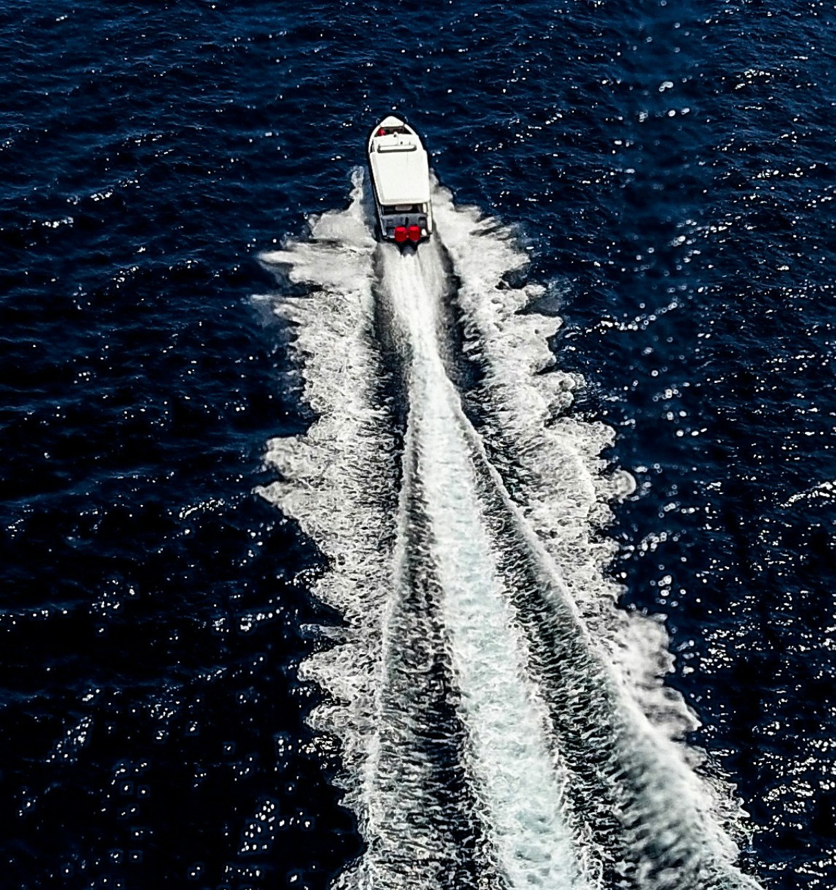 Aerial view of a boat cutting through dark blue water